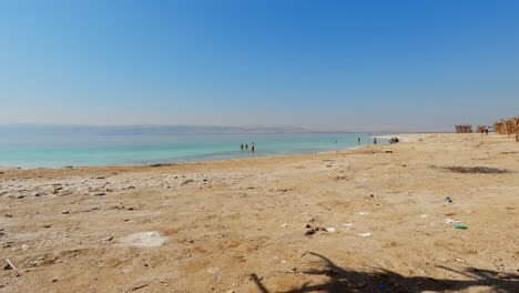 Weitwinkelblick-Von-Der-Tropischen-Cabana-Auf-Menschen,-Die-Im-Toten-Meer-Spielen-Und-Spazieren-Gehen