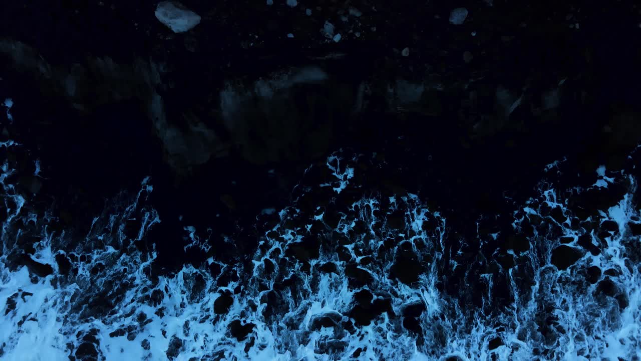 onde blu scuro si infrangono contro la scogliera