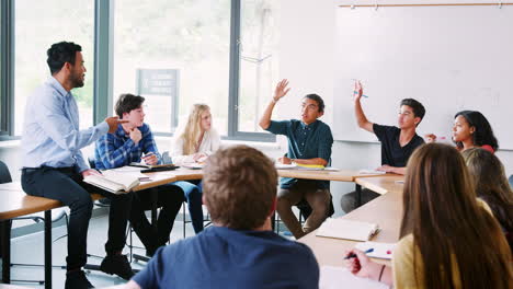 view through doorway of high school tutor sitting on desk teaching class