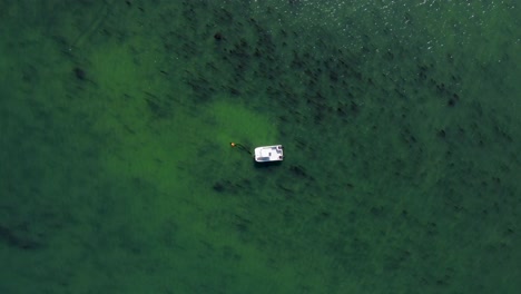 An-aerial-spinning-shot-of-the-sea,-off-the-coast-of-Whitstable-with-a-small-boat-in-the-middle