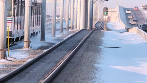 calgary light rail transit train kicks up snow on icy, sunny afternoon
