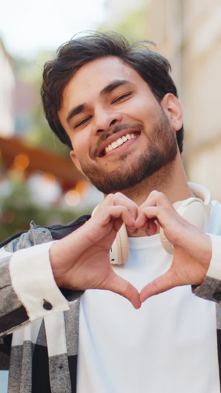 Indian man makes symbol of love showing heart sign to camera express romantic feelings on street