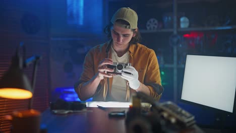 man repairing a vintage film camera in a darkroom style workshop