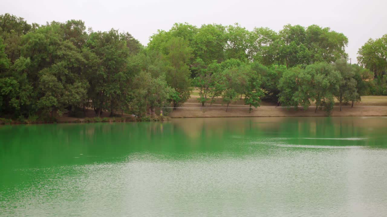 Peaceful view of "Lac de L'Orme Blanc" (a lake) in Caraman, France with line of trees on opposite bank
