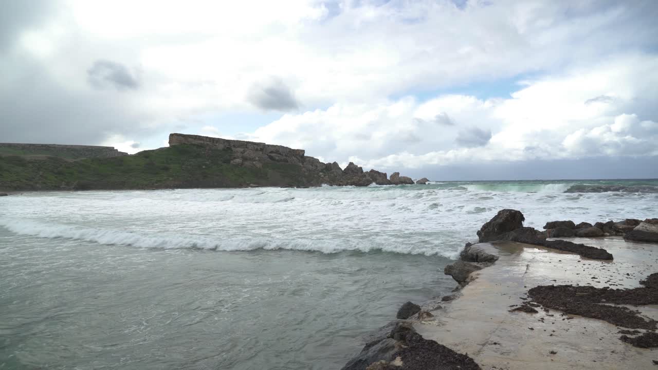 las mareas altas están rodando en la bahía de ghajn tuffieha en un sombrío día nublado y ventoso en malta