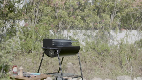 parrilla de barbacoa para fumar y mesa con especies en el jardín de verano