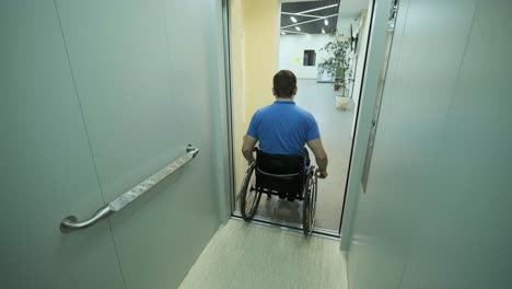 un hombre en silla de ruedas sale del ascensor. una persona con discapacidad viaja en un ascensor.