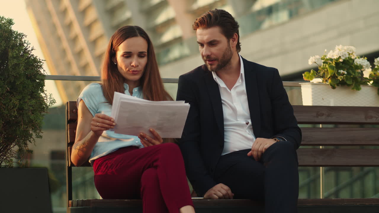 Partner commerciali seduti su una panchina in città. Colleghi che leggono documenti aziendali