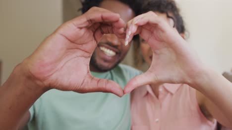 Happy-biracial-couple-gesturing-heart-sign-with-hands