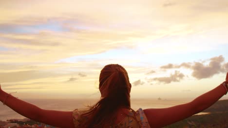 young girl lowering arms while looking at the sunset