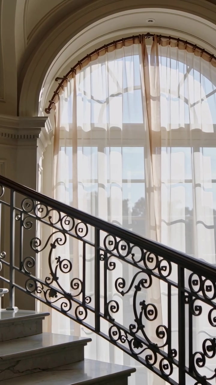 Vertical video: Panning camera showing wrought iron railing, arched window in foyer to show details