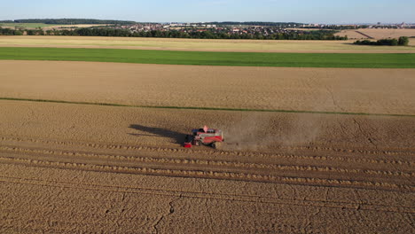 Cosechadora-De-Granos-En-El-Campo-Agrícola,-Máquina-Agrícola-Cosechando-Trigo-En-Una-Tarde-Soleada,-Vista-Aérea-De-Drones