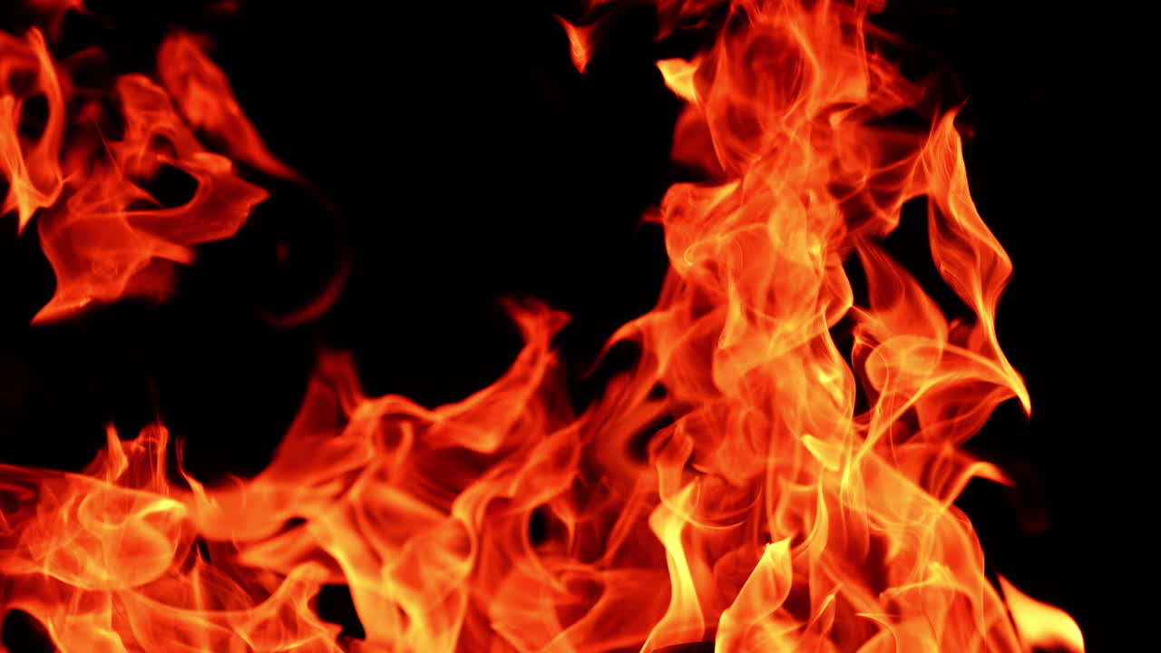 Orange flames of a campfire. Close up view on the big bonfire burning at black backdrop.