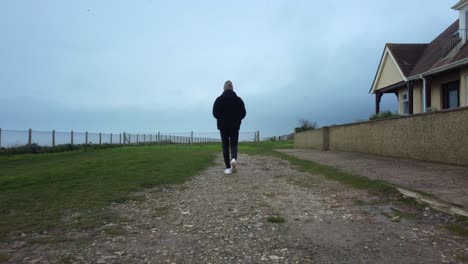 Siguiente-Hombre-Caminando-A-Lo-Largo-De-La-Ruta-Costera-Del-Acantilado-En-Tiempo-Nublado