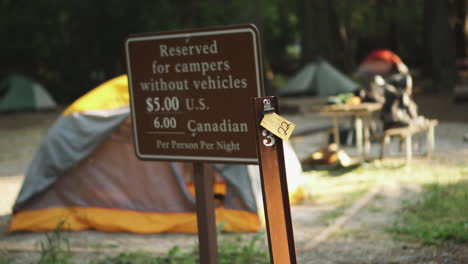 static view of a reserved area with blurred signboard indicating the amount to be paid for camping in glacier np campground and creek, united states