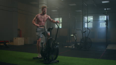 Joven-Usando-Bicicleta-Estática-En-El-Gimnasio.-Hombre-De-Fitness-Usando-Bicicleta-De-Aire-Para-Hacer-Ejercicio-Cardiovascular-En-El-Gimnasio.-Esfuerzo-Del-Equipo.