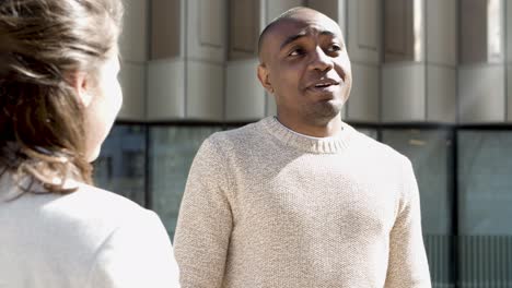 smiling african american man talking to friend on street