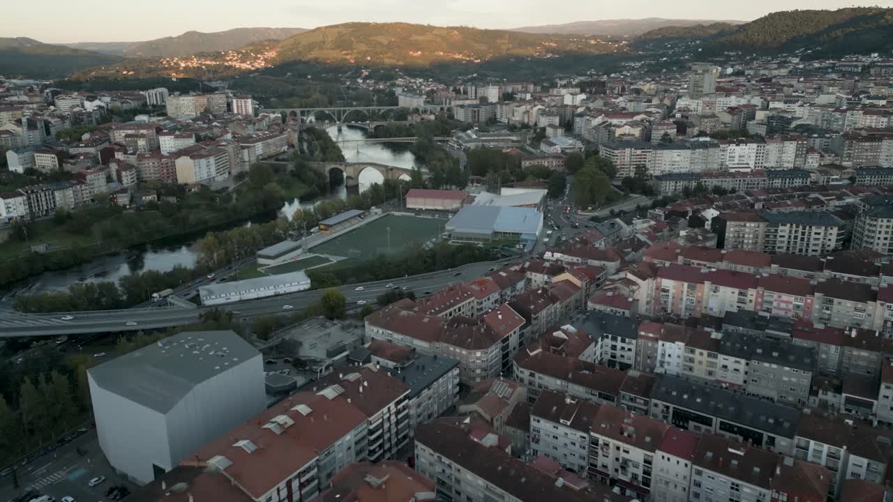 Veduta aerea panoramica della città di Ourense con vista sui ponti iconici che attraversano l'acqua al tramonto.