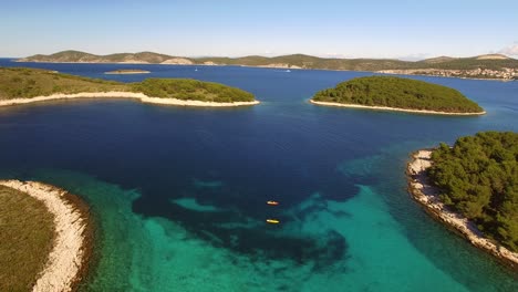 drone tilting from 2 kayaks and revealing blue lagoon with small islands