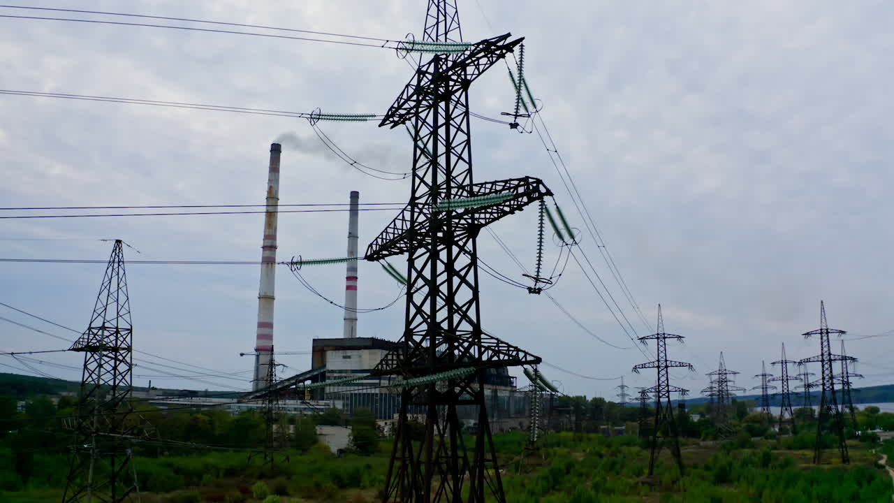 Electricity pylons and high-voltage power lines on the green grass. Power plant. Electrical power grid. View from the top.