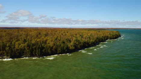 aerial orbiting shot of waves crashing along forest coastline