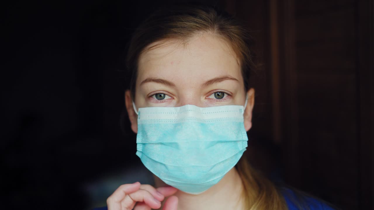 una mujer científica feliz y sonriente quitándose la máscara médica protectora