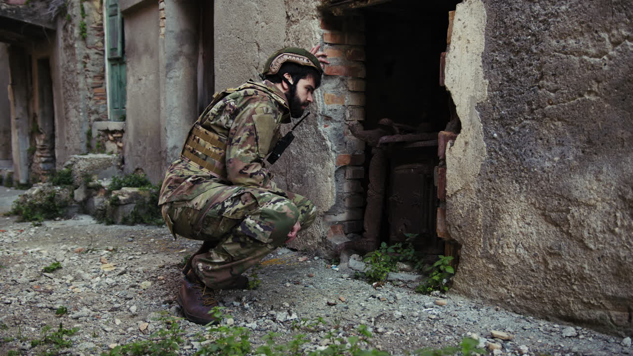 Soldier Looks Through The Destroyed Door Of An Old House