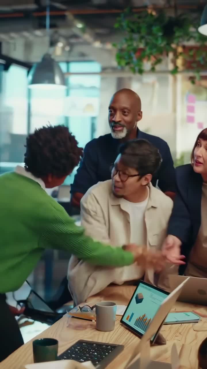 Video of a diverse team in a modern office, captured from a high angle, discussing data on a laptop