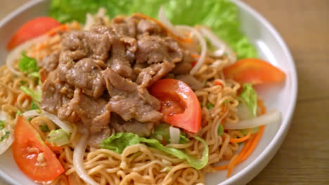 instant noodle spicy salad with pork on white plate - asian food style