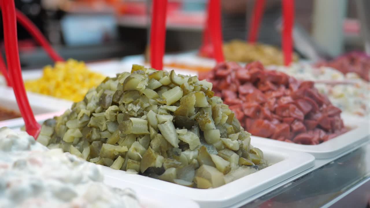 Mostrador de delicatessen exhibiendo varios ingredientes picados y ensaladas.