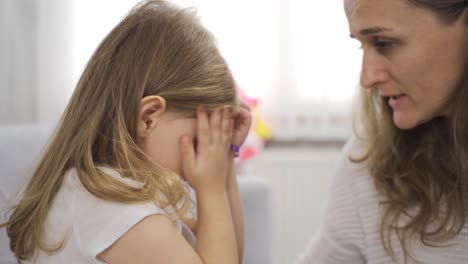 the little girl is crying and her mother is trying to talk to her.