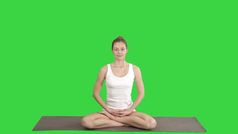 young beautiful blonde woman doing yoga and smiling on a green screen, chroma key