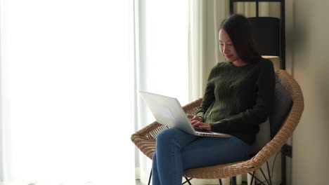 adult-Asian-woman-sitting-on-a-Rattan-chair-with-a-notebook-on-her-lap
