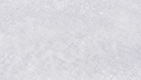 cold breeze blowing swirls of powdery snow over frozen white ground - detail shot