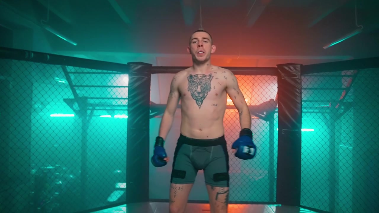 Beslutsom MMA-kæmper træner i et røgfyldt bur med dramatisk belysning