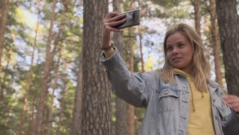 young girl making selfie at phone in sunny forest