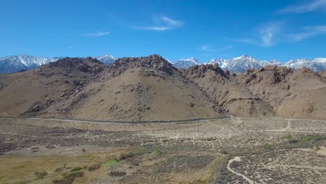 A-rising-aerial-over-the-Alabama-Hills-of-California-reveals-the-towering-and-snow-covered-Sierra-Nevada-mountains