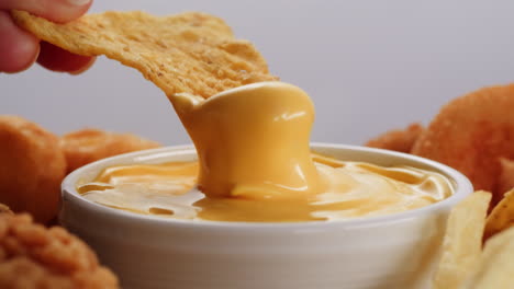 dipping a nacho chip in melted cheese sauce with other appetizers