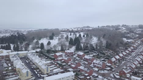 Forward-tracking-drone-shot-of-snowy-Exeter-over-a-wooded-area