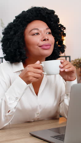 african american businesswoman drinks coffee thinking near window resting from work for inspiration