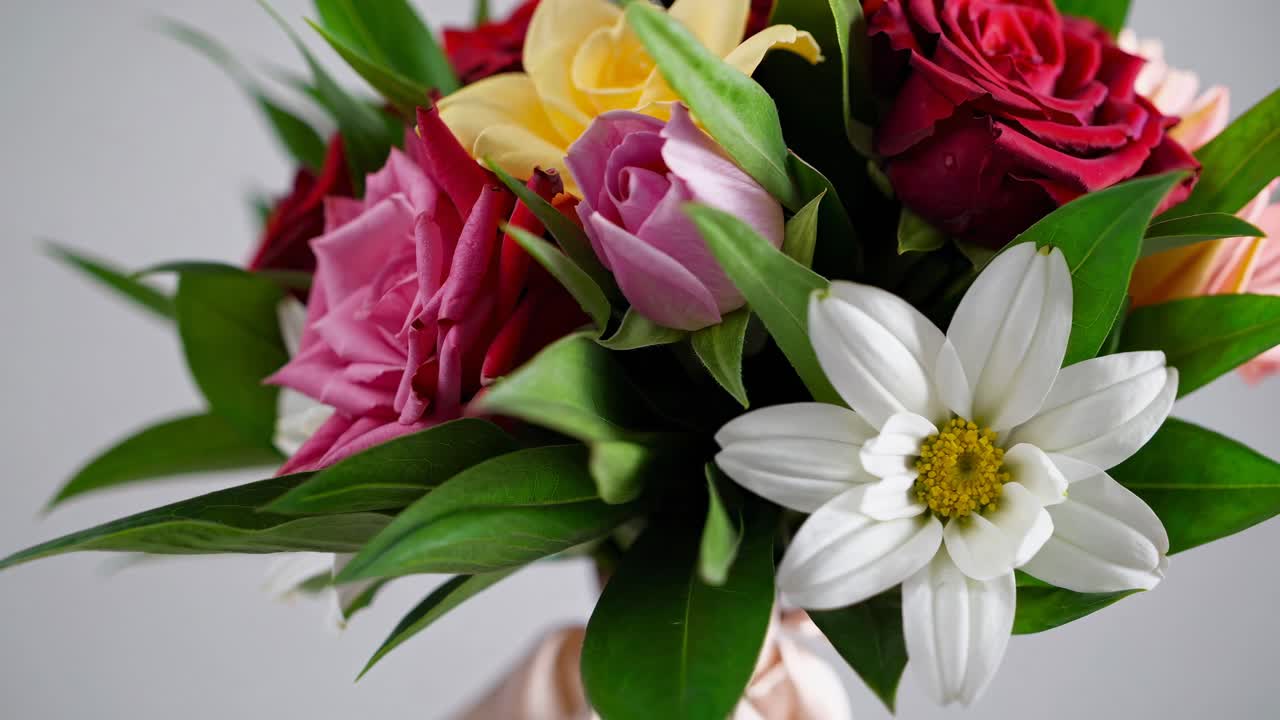 Close-up video shot of a vibrant flower bouquet with roses and daisies, showcasing rich colors