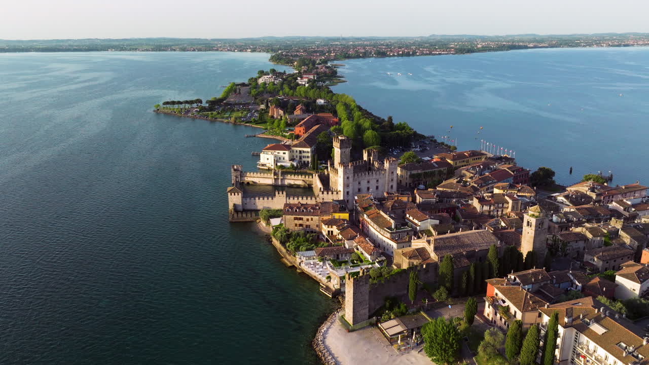 Sirimione Town In Lake Garda With Historical Castle At Sunrise In Italy. - aerial shot