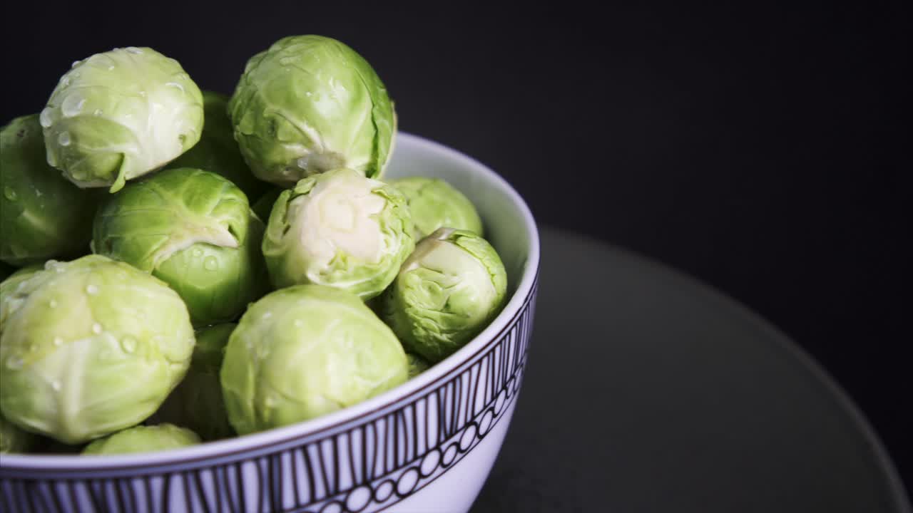 Schwenk nach rechts auf frischen Rosenkohl, der vor schwarzem Hintergrund rotiert.