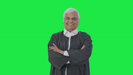 feliz abogado senior indio de pie con las manos cruzadas pantalla verde