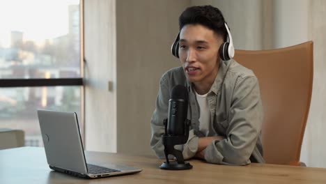 young asian speaker broadcasts live talking in microphone