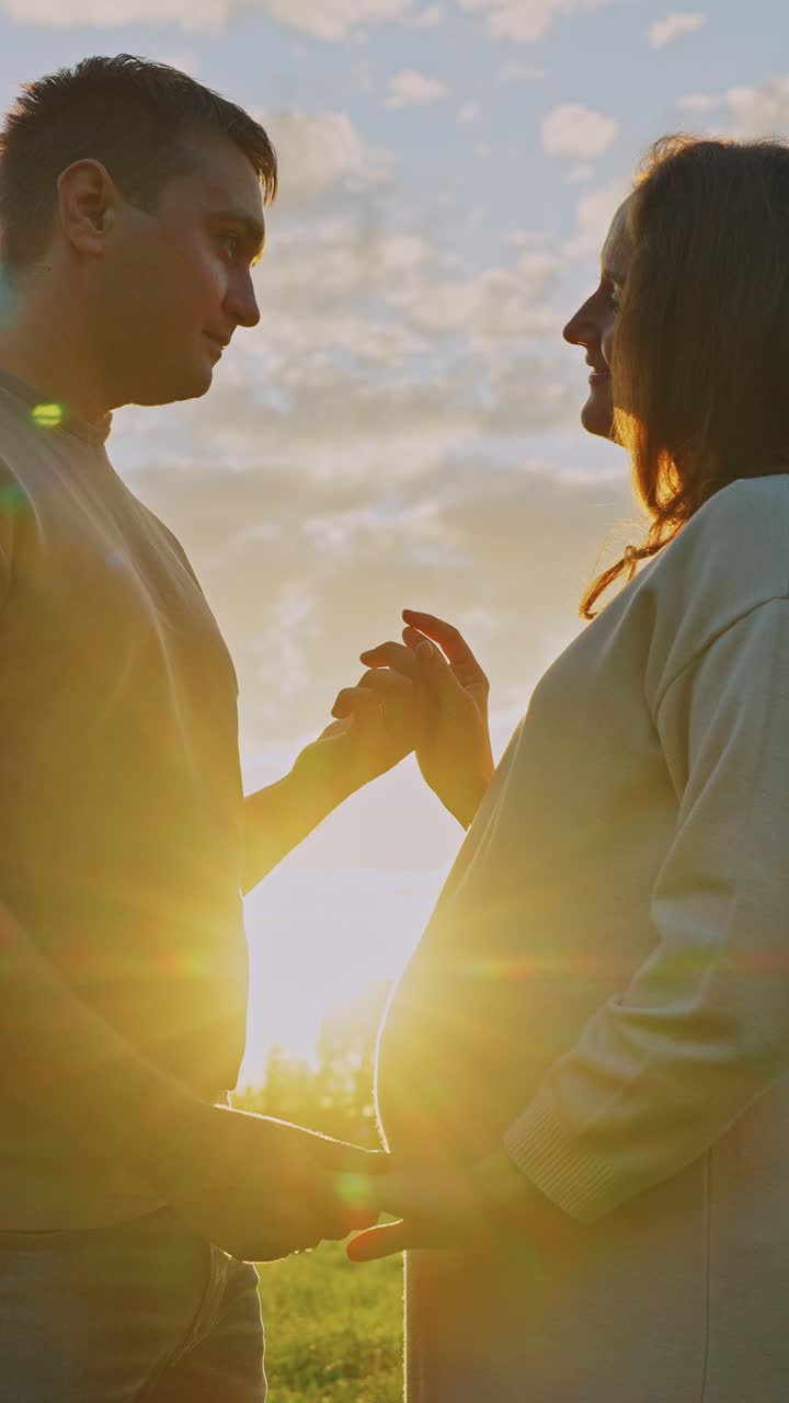 Pregnant Couple Holding Hands at Sunset