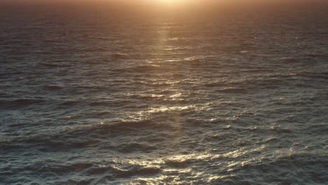 a low sunset reflects onto a choppy sea