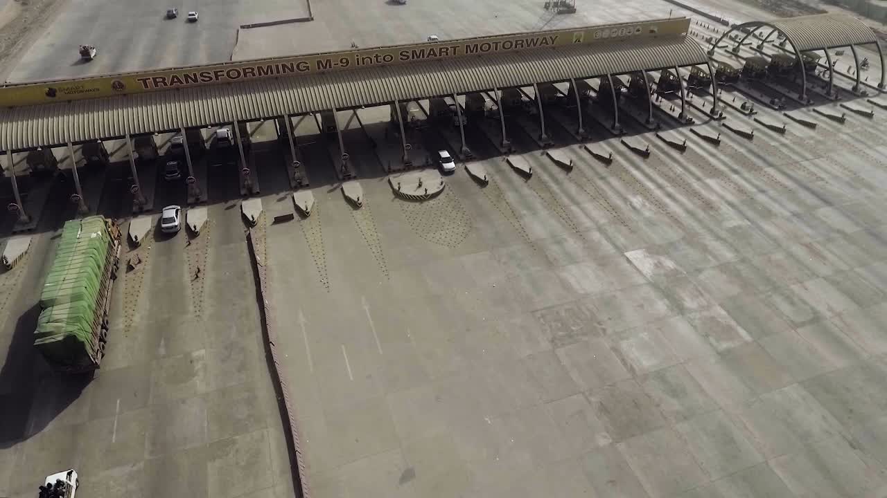 una vista aérea cercana de una plaza de peaje de la autopista de la ciudad, vehículos pesados y otros que ingresan y cruzan