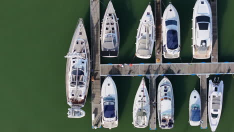 aerial shot birds-eye view panning over boats and yachts moored on jetty in boatyard 4k