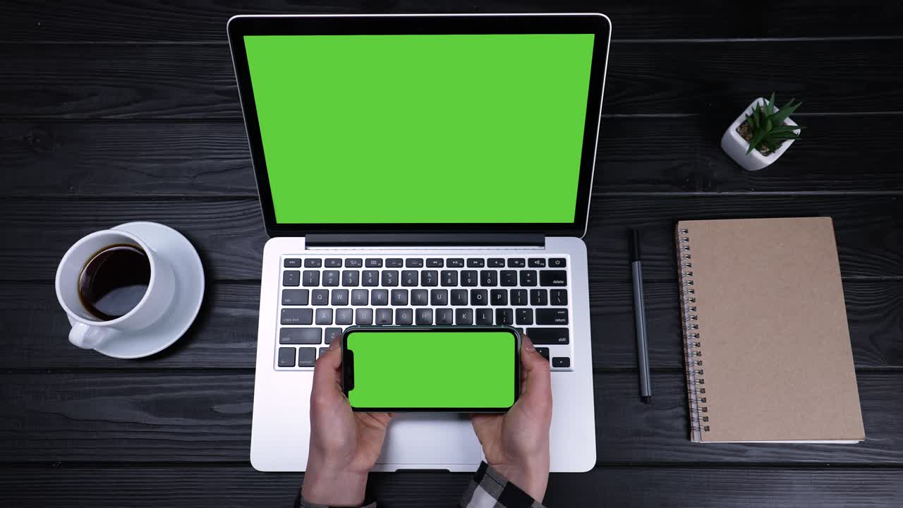 la chica trabaja usando varios dispositivos, portátil, teléfono inteligente. vista superior de una computadora portátil con pantalla verde y un teléfono con pantalla verde, que la chica sostiene en sus manos. cámara lenta. primer plano